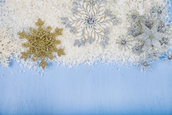 Flocons de neige décoratifs argentés et neige sur un fond de bois bleu — Photo