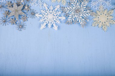 Mavi ahşap arka plan üzerinde gümüş dekoratif kar taneleri. İsa