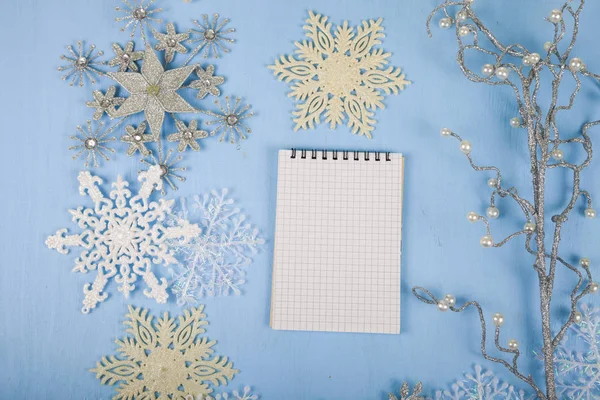 Fiocchi di neve decorativi d'argento e un taccuino su un bac di legno blu — Foto Stock