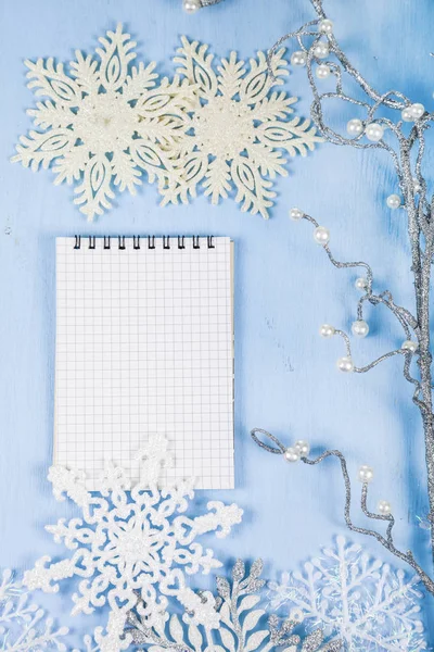 Copos de nieve decorativos de plata y un cuaderno en un bac de madera azul —  Fotos de Stock