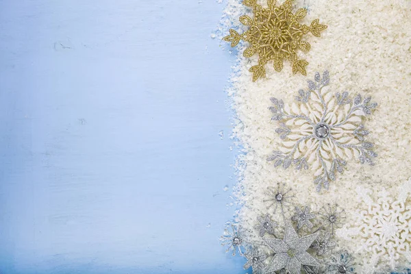 Серебряные декоративные снежинки и снег на синей деревянной спинке — стоковое фото