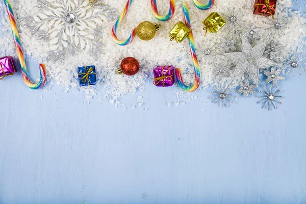 Zilveren decoratieve sneeuwvlokken en sneeuw op een blauwe houten pagina — Stockfoto