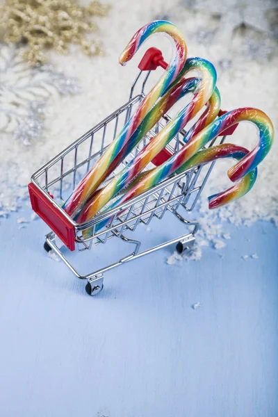 Shopping cart with Christmas candy in the snow. Concept of Chris