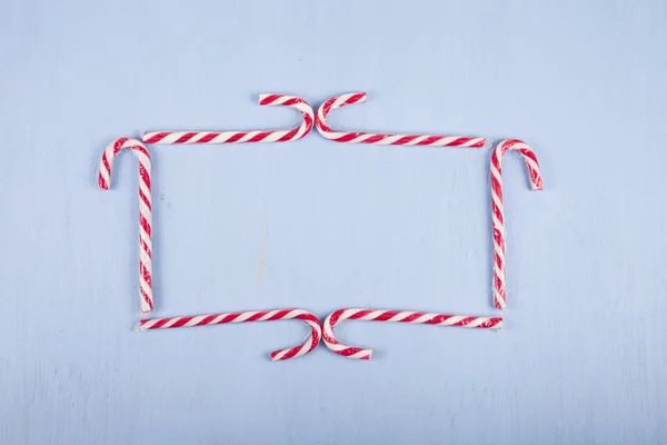 Cornice di bastoncini di zucchero su uno sfondo di legno. Dolci di Natale a — Foto Stock