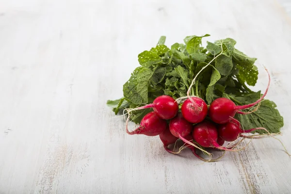 Mogna röda rädisor med lämnar på ett träbord närbild. Färska ve — Stockfoto