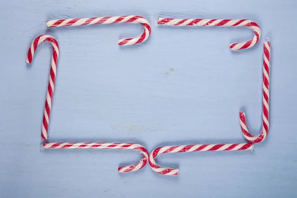 Cornice di bastoncini di zucchero su uno sfondo di legno. Dolci di Natale a — Foto Stock