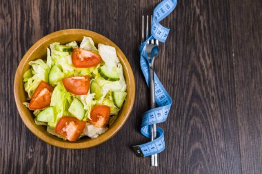 Ahşap kase ve karanlık tablo yakın çekim üzerinde ölçüm bandı salata