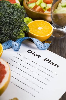Gıda ve koyu ahşap bir masa üzerinde bir diyet planı ile kağıt.