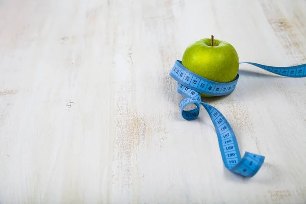 Manzana verde y cinta métrica en una mesa de madera. Concepto de morir —  Fotos de Stock