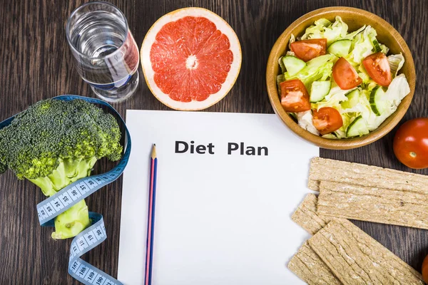 Food and sheet of paper with a diet plan on a dark wooden table. — Stock Photo, Image