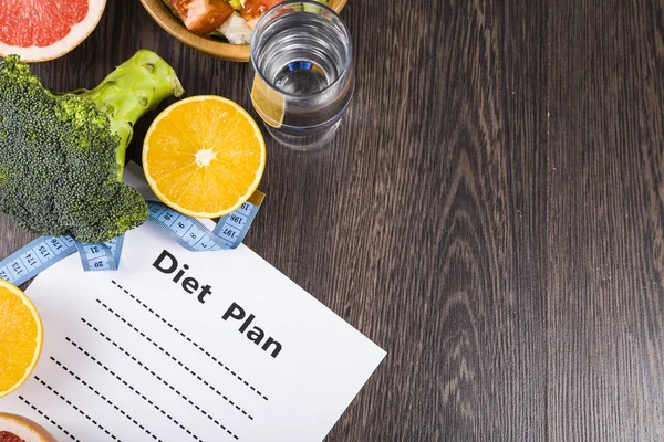 Gıda ve koyu ahşap bir masa üzerinde bir diyet planı ile kağıt.