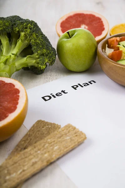 Food and sheet of paper with a diet plan on a  wooden table. — Stock Photo, Image