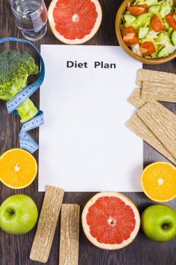 Gıda ve koyu ahşap bir masa üzerinde bir diyet planı ile kağıt.