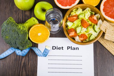 Gıda ve koyu ahşap bir masa üzerinde bir diyet planı ile kağıt.