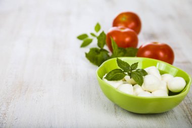 Mozzarella ahşap bir masa üzerinde yeşil bir tabak içinde. Mozzarella topları 