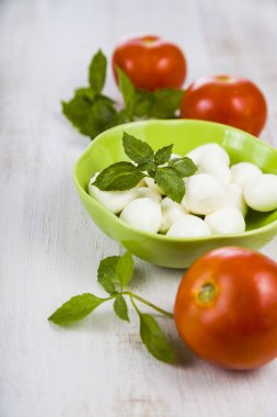 Mozzarella ahşap bir masa üzerinde yeşil bir tabak içinde. Mozzarella topları 