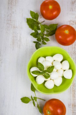 Mozzarella ahşap bir masa üzerinde yeşil bir tabak içinde. Mozzarella topları 