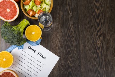 Gıda ve koyu ahşap bir masa üzerinde bir diyet planı ile kağıt.