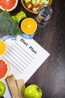 Gıda ve koyu ahşap bir masa üzerinde bir diyet planı ile kağıt.