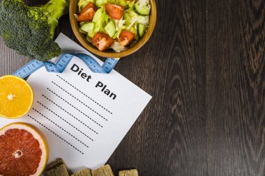 Gıda ve koyu ahşap bir masa üzerinde bir diyet planı ile kağıt.
