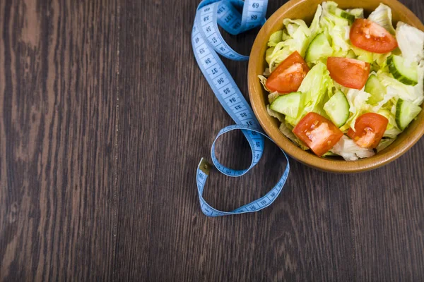 Ahşap kase ve karanlık tablo yakın çekim üzerinde ölçüm bandı salata