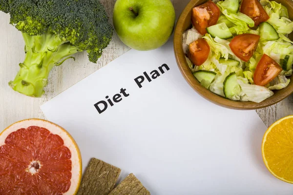 Food and sheet of paper with a diet plan on a  wooden table. — Stock Photo, Image