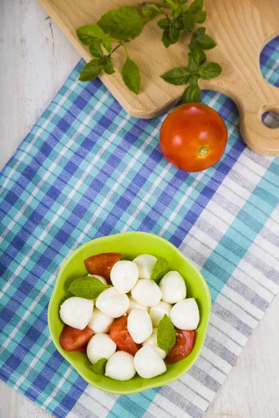 Mozzarella ahşap bir masa üzerinde yeşil bir tabak içinde. Mozzarella topları 