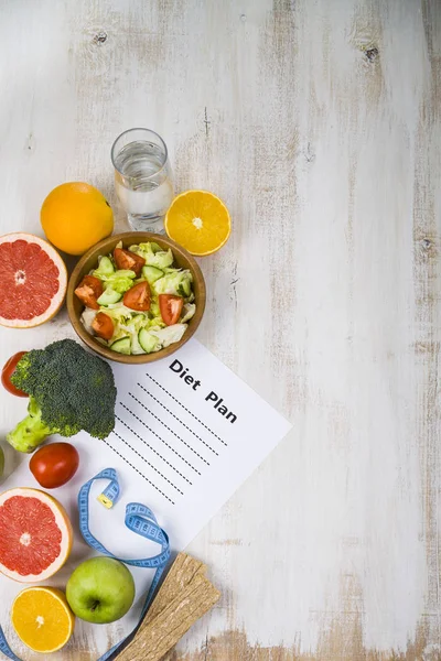 Food and sheet of paper with a diet plan on a  wooden table. Con — Stock Photo, Image