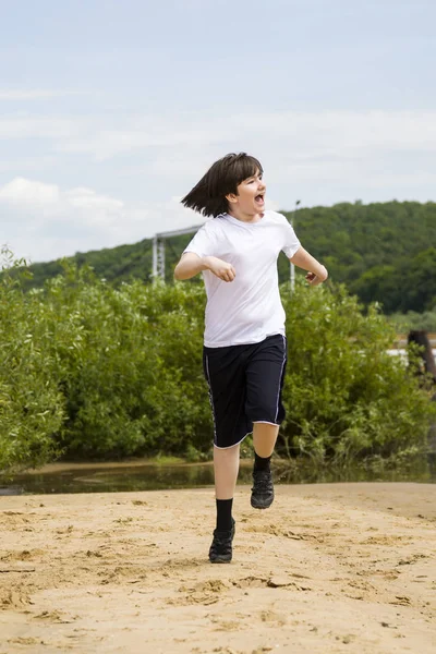 Glücklicher Teenager im weißen T-Shirt rennt an einem Sandstrand auf einem Sumo — Stockfoto