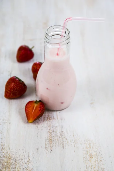 Smoothies e morango maduro em uma mesa de madeira . — Fotografia de Stock