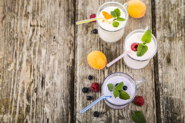Frullati o yogurt con bacche fresche su un tavolo di legno . — Foto Stock