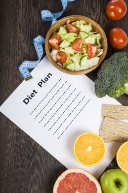 Gıda ve koyu ahşap bir masa üzerinde bir diyet planı ile kağıt.