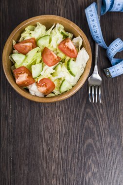 Ahşap kase, çatal ve karanlık tablo c ölçüm bandı salata