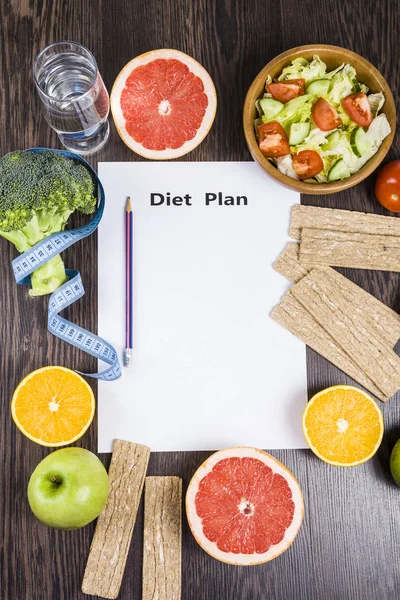 Gıda ve koyu ahşap bir masa üzerinde bir diyet planı ile kağıt. — Stok fotoğraf