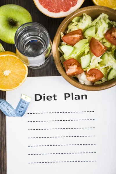 Lebensmittel und Blatt Papier mit Ernährungsplan auf einem dunklen Holztisch. — Stockfoto