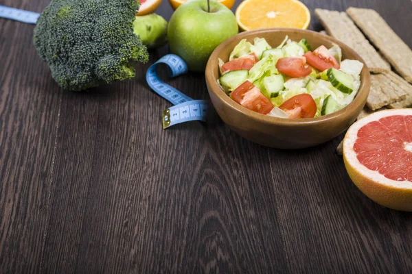 Voedsel voor dieet en het meetlint op een donkere houten tafel. — Stockfoto