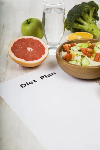 Food and sheet of paper with a diet plan on a  wooden table. — Stock Photo, Image