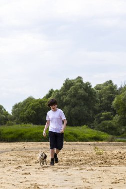 Çocuk ve kumlu bir plaj boyunca bir yaz gününde çalışan köpek