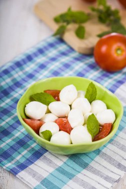 Mozzarella ahşap bir masa üzerinde yeşil bir tabak içinde. Mozzarella topları 