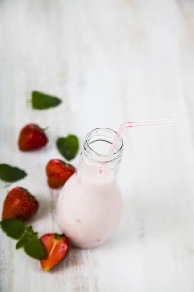 Smoothies e morango maduro em uma mesa de madeira . — Fotografia de Stock