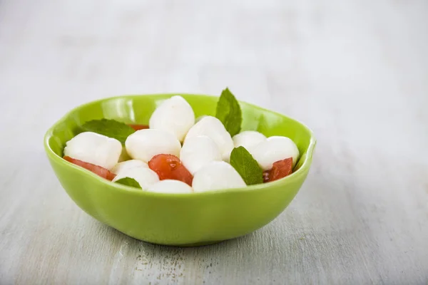 Mozzarella w zielony talerz na drewnianym stole. Mozzarella kulki — Zdjęcie stockowe