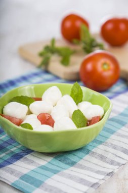 Mozzarella ahşap bir masa üzerinde yeşil bir tabak içinde. Mozzarella topları 
