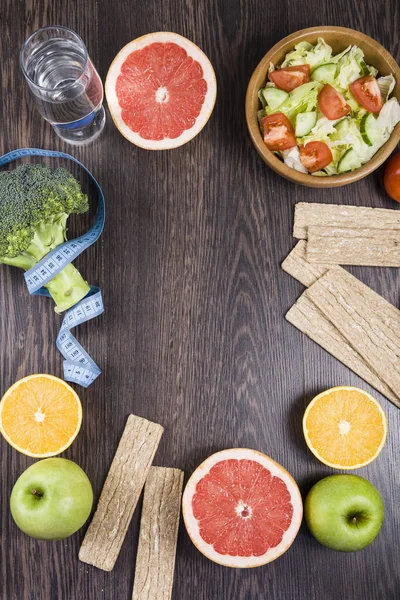 Voedsel voor dieet en het meetlint op een donkere houten tafel. — Stockfoto