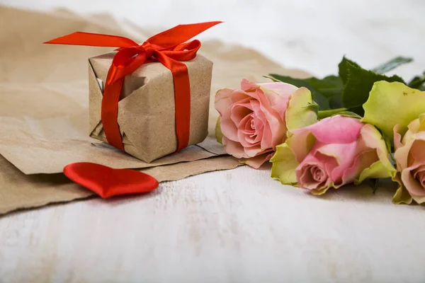 Rosas rosadas, regalos y corazones sobre un fondo de madera . —  Fotos de Stock