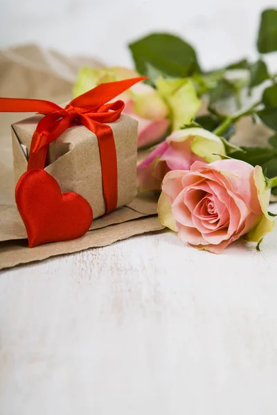 Rosas rosadas, regalos y corazones sobre un fondo de madera . —  Fotos de Stock