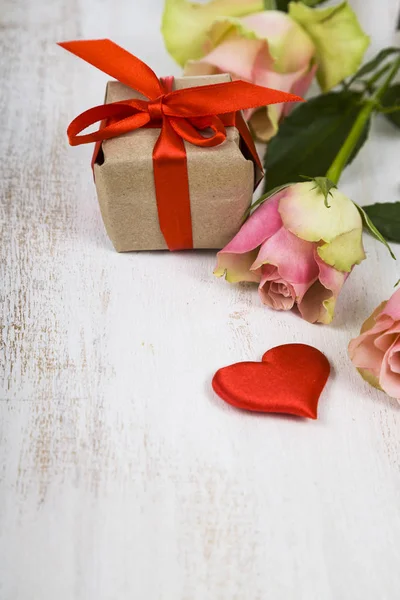 Рожеві троянди, подарунок і серця на дерев'яному фоні . — стокове фото