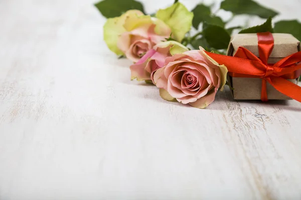 Rosa rosor och gåva på en trä bakgrund. — Stockfoto