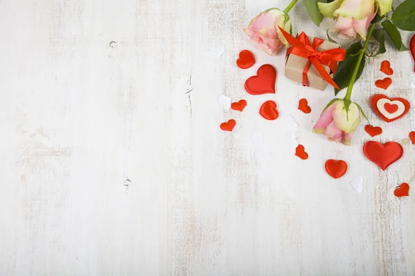 Rosas rosadas, regalos y corazones sobre un fondo de madera . — Foto de Stock