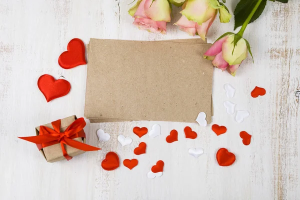 Pink roses, card, gift and hearts on a wooden background. — Stock Photo, Image