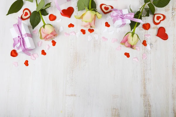 Rosa Rosen, Geschenk und Herzen auf einem hölzernen Hintergrund. — Stockfoto